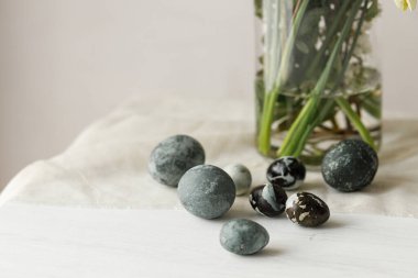 Mutlu Paskalyalar! Paskalya yumurtaları ve bahar çiçekleri köy odasındaki ahşap masa üzerinde. Paskalya modern basit dekorasyon, doğal boyanmış mermer yumurtalar. Mutlu Noeller.