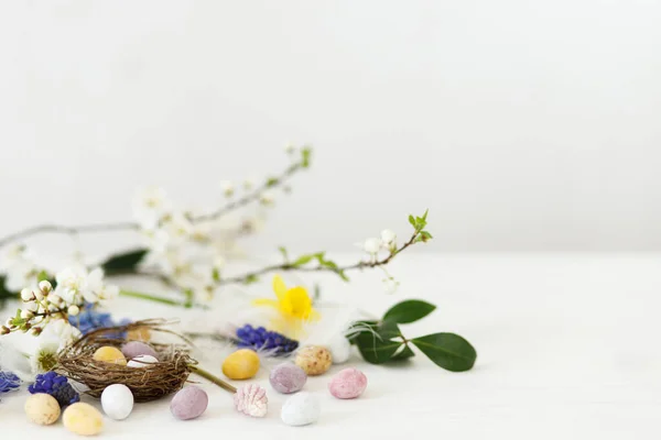 Frohe Ostern Stilvolle Osterschokoladeneier Nest Frühlingsblumen Federn Weißen Rustikalen Holztisch — Stockfoto