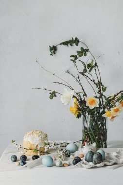 Paskalya yumurtaları, panettone ve bahar çiçekleri kırsal masada keten kumaş üzerinde. Doğal boya yumurtaları ve nergis buketi, şenlik için asgari yaşam. Mutlu Paskalyalar!