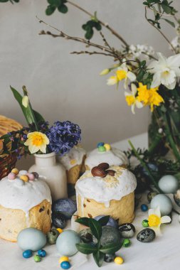 Paskalya yumurtaları, panettone, bahar çiçekleri ve kırsal ahşap masada çikolatalı yumurtalar. Doğal boya mermer yumurta, çiçek ve bayram yemeği. Şenlikli natürmort. Mutlu Paskalyalar!