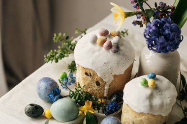 Mutlu Paskalyalar! Paskalya yumurtaları, ev yapımı paskalya ekmeği ve çarşaf peçetesinde bahar çiçekleri. Doğal boyanmış mermer yumurtalar, çiçekler ve bayram yemekleri. Modern hayat