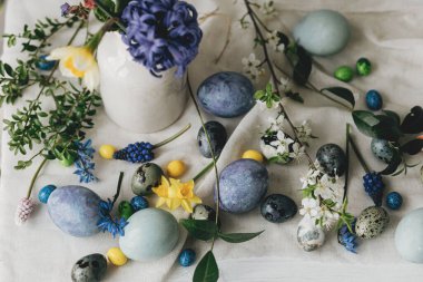 Mutlu Paskalyalar! Paskalya yumurtaları ve bahar çiçekleri kırsal masada keten peçete üzerinde. Doğal boyanmış mermer ve mavi yumurtalar, sümbül çiçekleri ve nergisler. Modern hayat