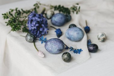 Mutlu Paskalyalar! Paskalya yumurtaları ve bahar çiçekleri kırsal masada keten peçete üzerinde. Doğal boyalı mermer ve mavi yumurta, sümbül çiçekleri ve keten peçete. Modern durgun yaşam