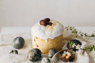 Mutlu Paskalyalar! Paskalya yumurtaları, ev yapımı paskalya ekmeği ve çarşaf peçetesinde bahar çiçekleri. Doğal boyanmış mermer yumurtalar ve kiraz çiçekleri, asgari yaşam.