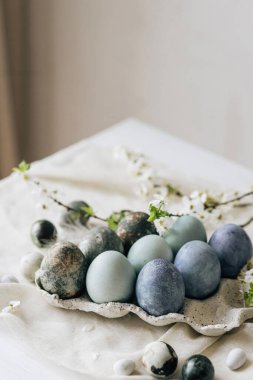 Mutlu Paskalyalar! Paskalya yumurtaları ve bahar çiçekleri keten kırsal masada. Doğal boyalı mermer mavi yumurtalar tepside ve kiraz çiçekleri. Modern durgun yaşam