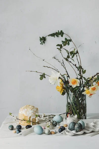 Paskalya yumurtaları, panettone ve bahar çiçekleri kırsal masada keten kumaş üzerinde. Doğal boya yumurtaları ve nergis buketi, şenlik için asgari yaşam. Mutlu Paskalyalar!
