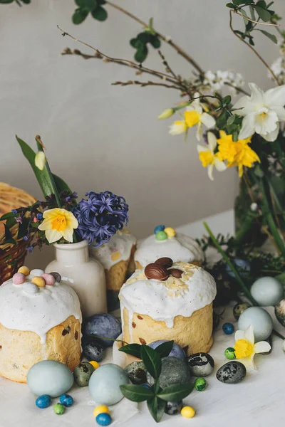 Paskalya yumurtaları, panettone, bahar çiçekleri ve kırsal ahşap masada çikolatalı yumurtalar. Doğal boya mermer yumurta, çiçek ve bayram yemeği. Şenlikli natürmort. Mutlu Paskalyalar!