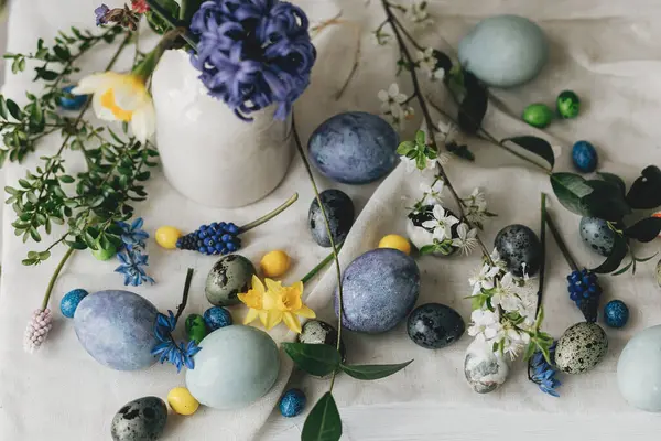 Mutlu Paskalyalar! Paskalya yumurtaları ve bahar çiçekleri kırsal masada keten peçete üzerinde. Doğal boyanmış mermer ve mavi yumurtalar, sümbül çiçekleri ve nergisler. Modern hayat