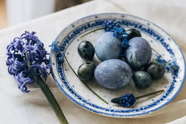 Mutlu Paskalyalar! Klasik tabakta paskalya yumurtaları keten peçetede bahar çiçekleri, kırsal masa ortamları. Doğal boyalı mavi yumurtalar ve sümbül çiçekleri. Modern durgun yaşam