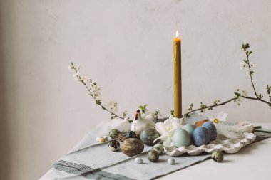 Paskalya yumurtaları tepside, kiraz çiçekleri ve kırsal masada mum. Mutlu Paskalyalar! Modern doğal boyanmış mermer yumurta ve bahar çiçekleri. Şenlikli kırsal yaşam