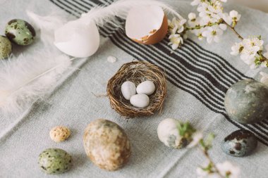 Paskalya yumurtaları ve kiraz çiçekli kompozisyonu köy masasında. Mutlu Paskalyalar! Modern doğal boyanmış mermer yumurta ve bahar çiçekleri. Kırsal yaşam