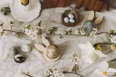 Paskalya yumurtaları, tavşanlar ve kırsal masada kiraz çiçekli kompozisyon. Mutlu Paskalyalar! Modern doğal boyanmış mermer yumurta ve bahar çiçekleri. Kırsal düzlük