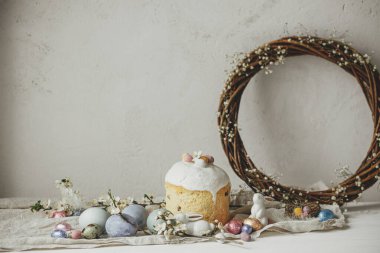 Mutlu Paskalyalar! Paskalya yumurtaları, pasta, tavşanlar, kiraz çiçekleri ve nergisler köy masasında. Modern doğal boyanmış yumurta, bayram yemeği ve bahar çiçekleri. Paskalya kırsalında hayat