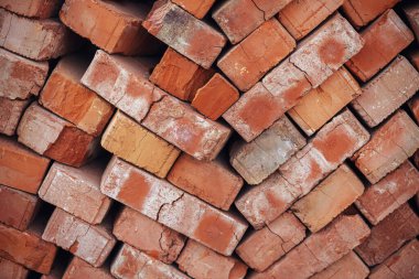 Stack of bricks masonry close up. Process of house building and building materials concept. Red bricks for laying at construction site. Brick wallpaper pattern