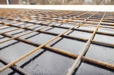 Reinforcement rods at construction site. Steel rebar mesh close up. Rusty steel reinforcement bars for concrete foundation or ceiling. Process of house building