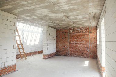 Unfinished house inside. Aerated concrete blocks and brick walls with windows, doorways and concrete floor. Process of house building at construction site. New house construction
