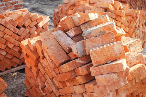 Stack of red bricks, process of house building. Bricks for laying on concrete foundation. Building materials at construction site