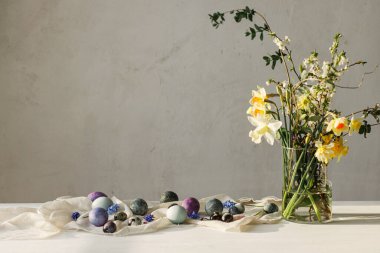 Paskalya yumurtaları ve kır ağacından yapılmış masa üzerinde bahar çiçekleri. Paskalya modern basit dekorasyon, doğal boyanmış mermer yumurtalar. Mevsimler selamlar. Mutlu Paskalyalar!