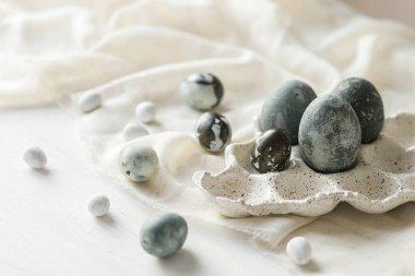 Mutlu Paskalyalar! Modern tepside paskalya yumurtaları ve kırsal beyaz masa üzerinde keten kumaş. Doğal boyalı mermer yumurtalar, asgari yaşam. Mevsimler selamlar