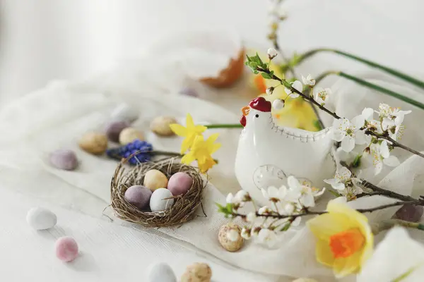 Osterstillleben Bunte Osterschokoladeneier Nest Frühlingsblumen Hühnerfiguren Komposition Auf Weißem Holztisch — Stockfoto