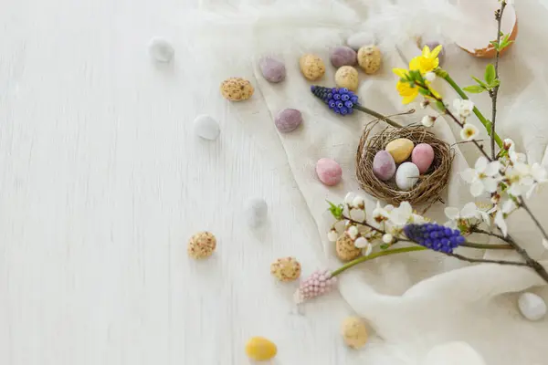 Bunte Osterschokoladeneier Nest Frühlingsblumen Federn Und Leineneinfassung Auf Weißem Holztisch — Stockfoto