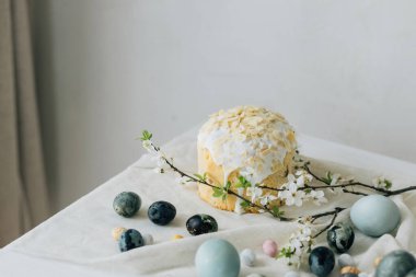 Paskalya yumurtaları, panettone ve bahar çiçekleri kırsal masada keten kumaş üzerinde. Doğal boya yumurtaları ve kiraz çiçekleri, şenlik için asgari yaşam. Mutlu Paskalyalar!