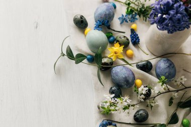 Mutlu Paskalyalar! Paskalya yumurtaları ve bahar çiçekleri kırsal masada keten peçete üzerinde. Doğal boyanmış mermer ve mavi yumurtalar, sümbül çiçekleri ve nergisler. Modern minimal düz yatak