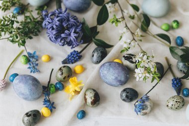 Paskalya düzlüğü. Paskalya yumurtaları ve bahar çiçekleri kırsal masada keten peçete üzerinde. Mutlu Paskalyalar! Doğal boyanmış mermer ve mavi yumurtalar, sümbül çiçekleri. Modern hayat