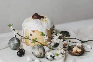 Mutlu Paskalyalar! Paskalya yumurtaları, ev yapımı paskalya ekmeği ve çarşaf peçetesinde bahar çiçekleri. Doğal boyanmış mermer yumurtalar ve kiraz çiçekleri, asgari yaşam.