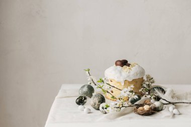 Mutlu Paskalyalar! Paskalya yumurtaları, ev yapımı paskalya ekmeği ve çarşaf peçetesinde bahar çiçekleri. Doğal boyanmış mermer yumurtalar ve kiraz çiçekleri, asgari yaşam.