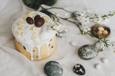 Mutlu Paskalyalar! Paskalya yumurtaları, ev yapımı paskalya ekmeği ve çarşaf peçetesinde bahar çiçekleri. Doğal boyanmış mermer yumurtalar ve kiraz çiçekleri, asgari yaşam.