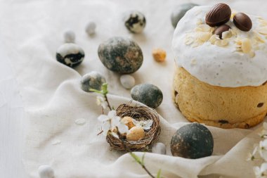 Paskalya yumurtaları, panettone, bahar çiçekleri ve çarşaf örtüsü üzerinde çikolata yumurtaları. Doğal boya mermer yumurtalar ve kiraz çiçekleri, asgari yaşam. Mutlu Paskalyalar!