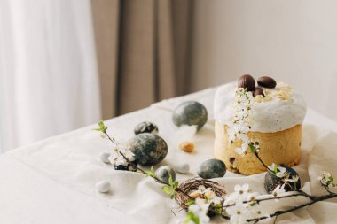 Mutlu Paskalyalar! Paskalya yumurtaları, ev yapımı paskalya ekmeği ve çarşaf peçetesinde bahar çiçekleri. Doğal boyanmış mermer yumurtalar ve kiraz çiçekleri, asgari yaşam.