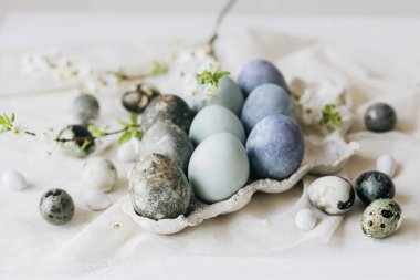 Mutlu Paskalyalar! Paskalya yumurtaları ve bahar çiçekleri keten kırsal masada. Tepside doğal boyanmış mermer yumurtalar ve kiraz çiçekleri. Modern durgun yaşam