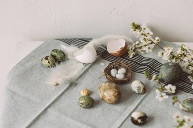 Mutlu Paskalyalar! Yuvada zarif paskalya yumurtaları ve kırsal masada kiraz çiçekleri. Modern doğal boyanmış mermer yumurta ve bahar çiçekleri. Paskalya 'da kırsal evdeki hayat dekorasyonu