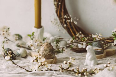 Mutlu Paskalyalar! Paskalya yumurtaları, tavşanlar ve kiraz çiçekleri köy masasında. Modern doğal boyanmış mermer yumurta ve bahar çiçekleri. Paskalya 'da kırsal evdeki hayat dekorasyonu