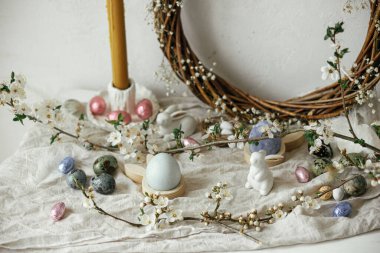 Paskalya yumurtaları, tavşanlar ve kırsal masada kiraz çiçekli kompozisyon. Mutlu Paskalyalar! Modern doğal boyanmış, çikolatalı yumurta ve bahar çiçekleri. Kırsal yaşam