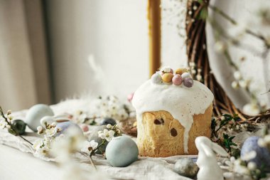 Mutlu Paskalyalar! Paskalya yumurtaları, pasta, tavşanlar, kiraz çiçekleri ve nergisler köy masasında. Modern doğal boyanmış yumurta, bayram yemeği ve bahar çiçekleri. Paskalya kırsalında hayat