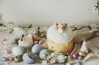 Mutlu Paskalyalar! Paskalya yumurtaları, pasta, tavşanlar, kır masasında kiraz çiçekleri. Modern doğal boyanmış yumurta, bayram yemeği ve bahar çiçekleri. Paskalya kırsalında hayat