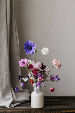 Vazoda yaz çiçekleri, kırsal yaşam. Güzel renkli şakayık, ranunculus, keten perdeli eski ahşap bankta latilus. Çiçekli karamsar duvar kâğıdı. Metin için boşluk