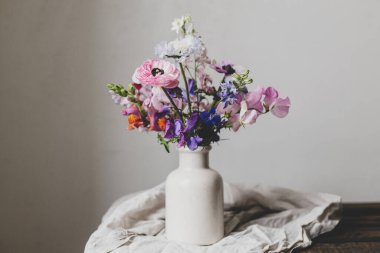 Summer flowers in vase, rustic moody still life. Beautiful colorful anemone, ranunculus, lathyrus, scabiosa on aged bench with linen cloth. Floral moody wallpaper. Space for text clipart