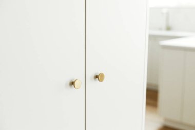 Modern mutfak iç mimarisi. Yeni İskandinav evinde pirinçten düğmeli şık beyaz mutfak dolapları. Temizlik dolabı. Modern mutfak tasarımı. Depolama
