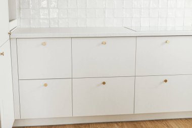 Modern mutfak iç mimarisi. Pirinç düğmeli şık beyaz mutfak dolapları, granit tezgah ve yeni İskandinav evinde elektrikli soba. Modern mutfak atölyesi