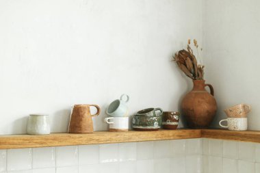 Yeni İskandinav evinde modern mutfağın arka planında fincanlar ve dekorla ahşap bir raf. Modern mutfak iç mimarisi ve şık çiftlik aletleri.