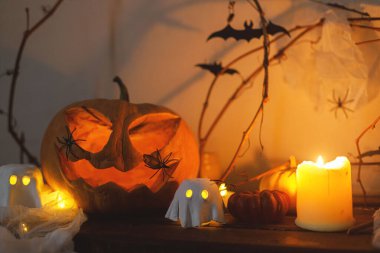 Korkunç Jack o fener kabağı, parlayan hayaletler, akşamları örümcekler ve yarasalar. Mutlu Cadılar Bayramı! Masada atmosferik cadılar bayramı dekorasyonu, metin için boşluk. Şaka mı şeker mi?