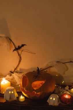 Mutlu Cadılar Bayramı! Ürkütücü Jack o fener kabağı, parlayan hayaletler, karanlıkta örümcekler ve yarasalar. Masada atmosferik cadılar bayramı dekoru var. Şaka mı şeker mi?