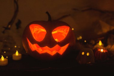 Mutlu Cadılar Bayramı! Ürkütücü Jack o fener kabağı, parlayan hayaletler, karanlıkta örümcekler ve yarasalar. Masada atmosferik cadılar bayramı dekoru var. Şaka mı şeker mi?