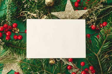 Noel kartı maketi. Boş tebrik kartı dairesi, köknar dalları, kırmızı böğürtlen ve yeşil arkaplanda parıltılı süsler ile yatıyordu. Mutlu noeller. Season selamlama şablonu