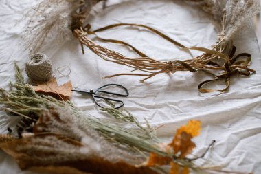 Şık bir sonbahar çelengi yapmak. Kurumuş ot, otlar, yapraklar, kurdele ve makas kırsal masada. Sonbahar dekoru ve evdeki düzenleme detayları. Şükran Günü ve Cadılar Bayramı