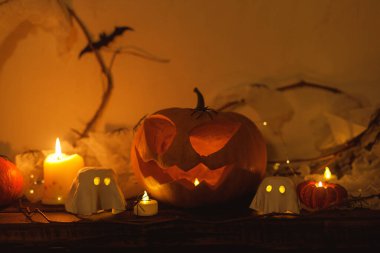 Korkunç Jack o fener kabağı, parlayan hayaletler, akşamları örümcekler ve yarasalar. Mutlu Cadılar Bayramı! Masada atmosferik cadılar bayramı dekorasyonu, metin için boşluk. Şaka mı şeker mi?